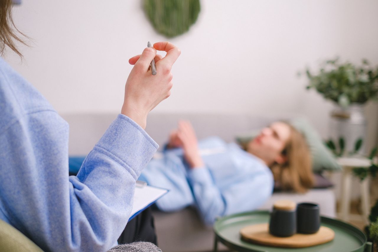 about-us Therapist taking notes during a therapy session with a relaxed client lying on a couch.